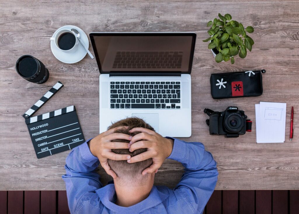 Man sitzt verzweifelt vor seinem Laptop am Schreibtisch